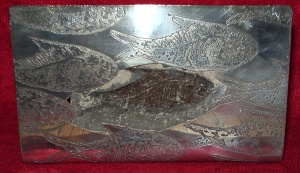 Silver ornament based on a fossil fish withe etched shoal